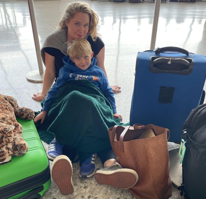 The author and her son sit with their luggage in an airport.