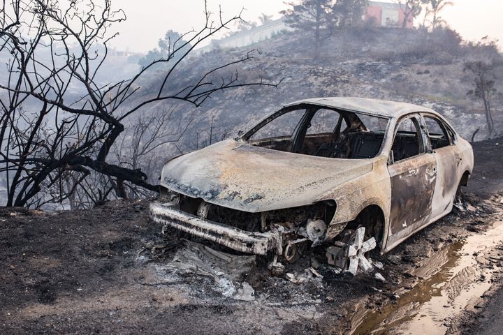 Remains of a burnt car on the side of Pacific Coast Highway after the Woolsey Fire swept through in 2018. Some wealthy Angelenos hired private firefighters to protect their mansions from burning.